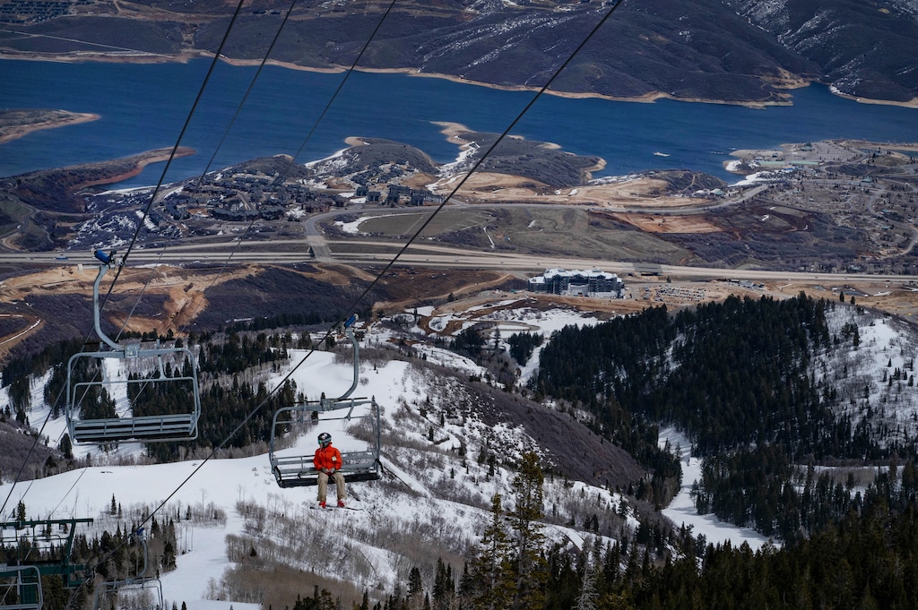 (Francisco Kjolseth | The Salt Lake Tribune) A skier rides the Sultan Express lift as the Deer Valley East Village undergoes construction along U.S. 40 and Jordanelle Reservoir on Thursday, April 4, 2024. The resort will open some 300 acres of terrain in the Deer Valley East Village area this winter. Eventually, it will offer 3,700 additional acres of skiable terrain.