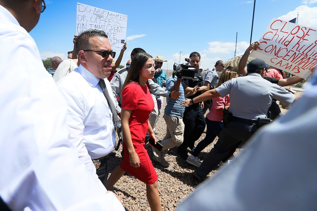 (Briana Sanchez | El Paso Times | AP) U.S. Rep. Alexandria Ocasio-Cortez, D-New York, is escorted back to her vehicle after she speaks at the Border Patrol station in Clint about what she saw at area border facilities Monday, July 1, at the station in Clint.
