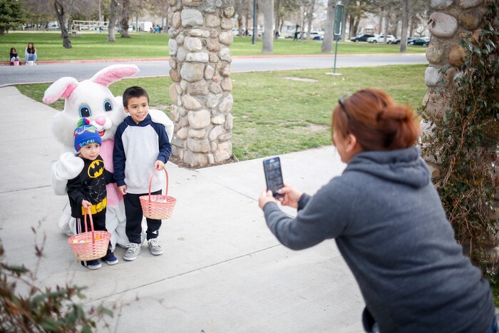 (Nicole Boliaux | For The Tribune) Eva Rivera takes pictures of her sons Michael, right, and left, with the Easter Bunny during the annual Easter egg hunt put on by A Kid's Place Dentistry in Liberty Park in Salt Lake City on Saturday, March 31, 2018.