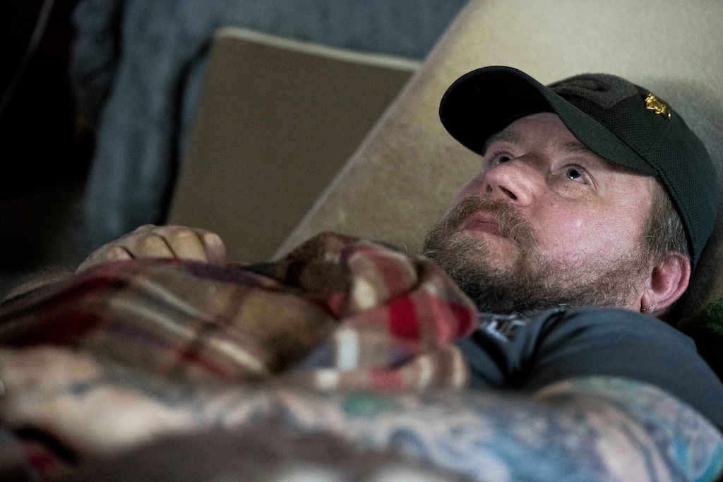 In this Friday, Nov. 16, 2018 photo, Jim Taft watches The History Channel from the confines of his bed at his home in West Columbia, S.C. Taft has experienced debilitating health issues after a neurosurgeon implanted Boston Scientific's Precision spinal cord stimulator in his back in 2014. (AP Photo/Sean Rayford)