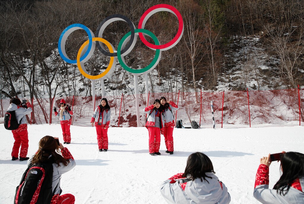 Volunteers take photos in front of the Olympic rings near the finish area during men's downhill training at the 2018 Winter Olympics in Jeongseon, South Korea, Friday, Feb. 9, 2018. (AP Photo/Christophe Ena)