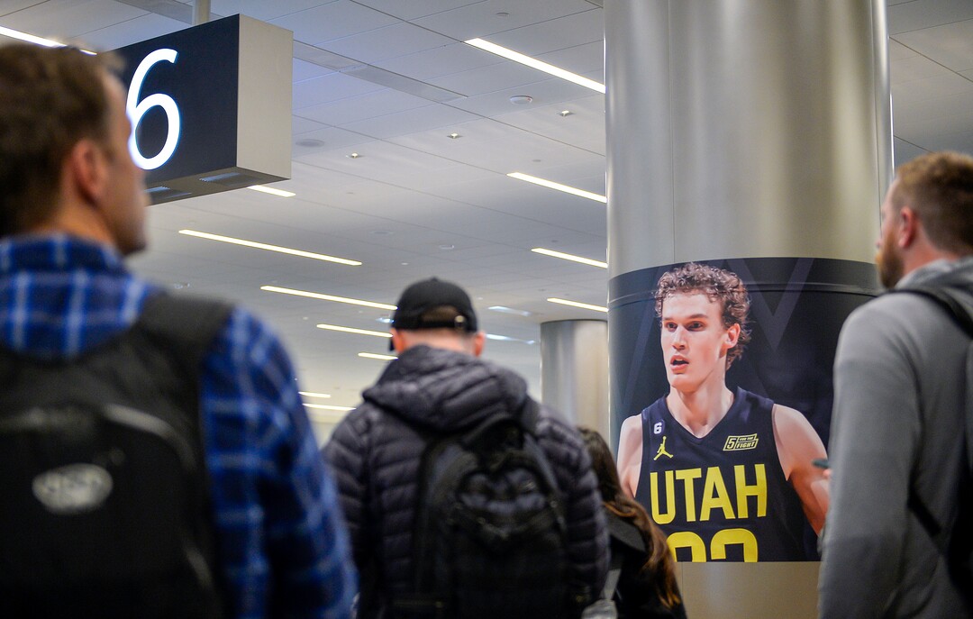 (Chris Samuels | The Salt Lake Tribune) Passengers collect baggage in front of a poster of Lauri Markkanen All-Star Game signage at Salt Lake City International Airport, Friday, Feb. 17, 2023.