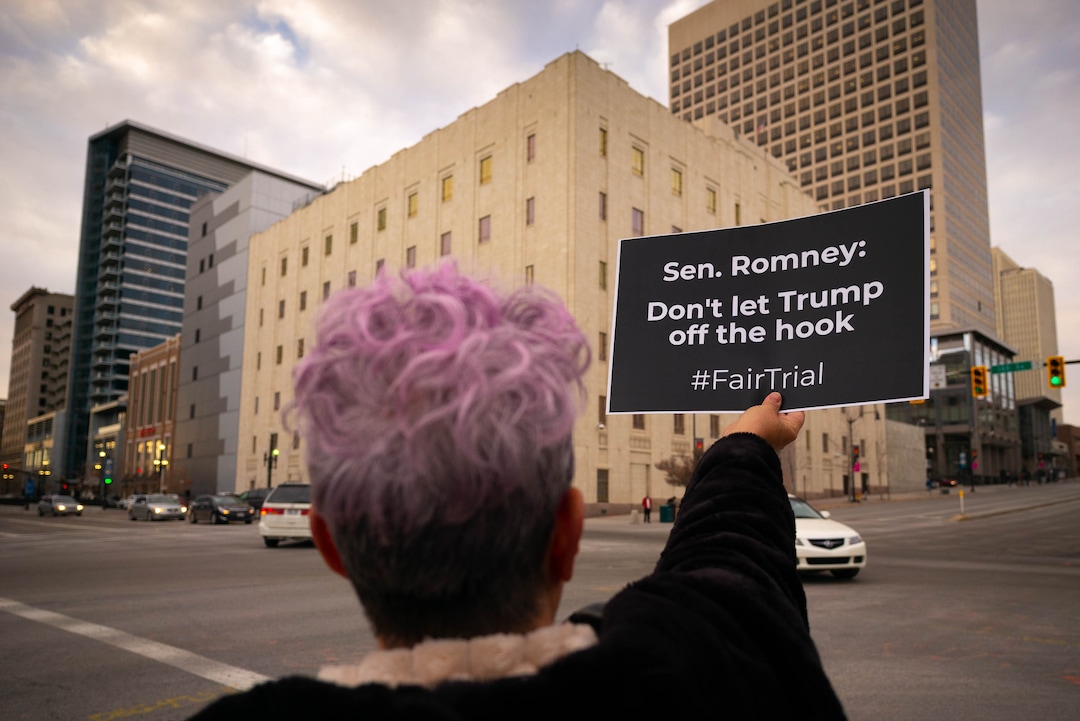 (Trent Nelson  |  The Salt Lake Tribune) Deborah Dick holds a sign to passing traffic as a coalition of progressive groups gathered Thursday outside the federal building in Salt Lake City on Thursday, Jan. 16, 2020 to push for a fair and impartial Senate impeachment hearing against President Donald Trump.