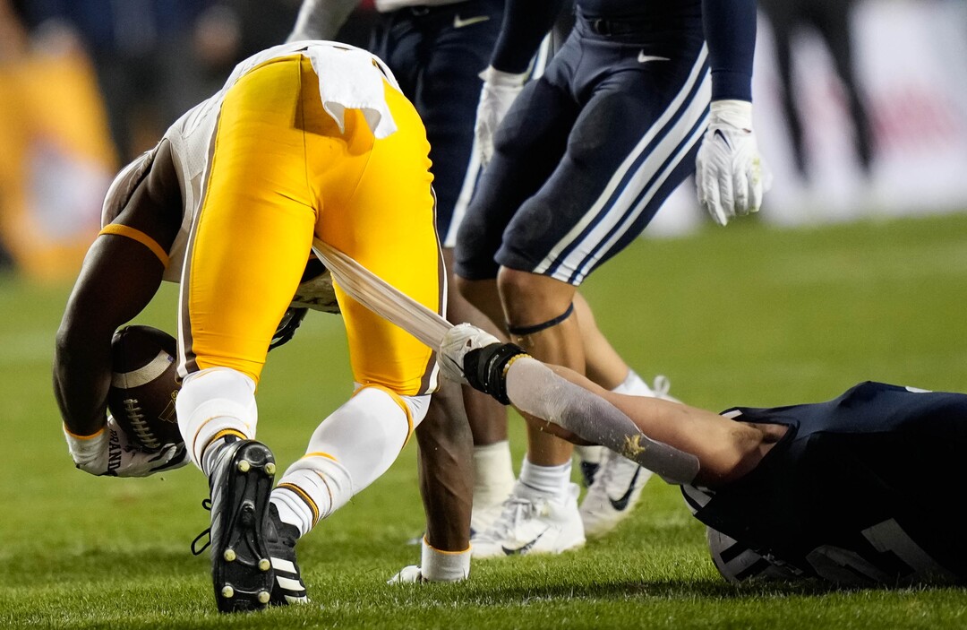 (Francisco Kjolseth | The Salt Lake Tribune) Wyoming Cowboys running back Titus Swen (2) has his towel pulled on by Brigham Young Cougars linebacker Ben Bywater (2) in football action between the Brigham Young Cougars and the Wyoming Cowboys at LaVell Edwards Stadium in Provo, on Saturday, Sept. 24, 2022.