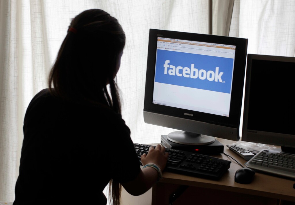 FILE - In this June 4, 2012, file photo, a girl looks at Facebook on her computer in Palo Alto, Calif. Baffled in 2016 by Russian agents who bought ads in an attempt to sway the U.S. presidential campaign, Facebook told the National Association of Secretaries of State on Saturday, Feb. 17, 2018, that the company would send postcards to potential buyers of political ads to confirm they reside in the U.S. The plan was unveiled a day after special counsel Robert Mueller charged 13 Russians with interfering in the presidential election. (AP Photo/Paul Sakuma, File)