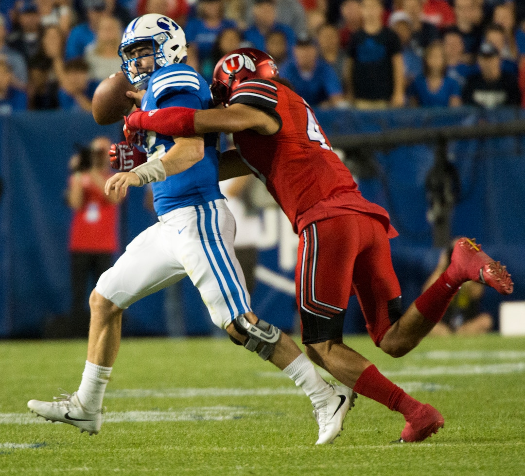 (Rick Egan  |  The Salt Lake Tribune)   Brigham Young Cougars quarterback Tanner Mangum (12) tries to pass as he is grabbed from behind by Utah Utes defensive end Caleb Repp (47), in football action BYU vs Utah, at Lavell Edwards Stadium in Provo, Saturday, September 9, 2017.