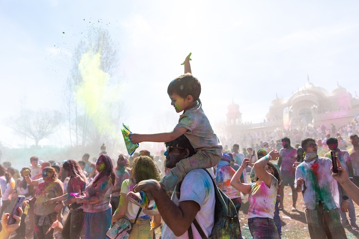 (Rachel Rydalch | The Salt Lake Tribune) A young boy sits on a mans shoulders and throws colors into the air to celebrate the new Spring at the Festival of Colors in Spanish Fork on Saturday, March 26, 2022.
