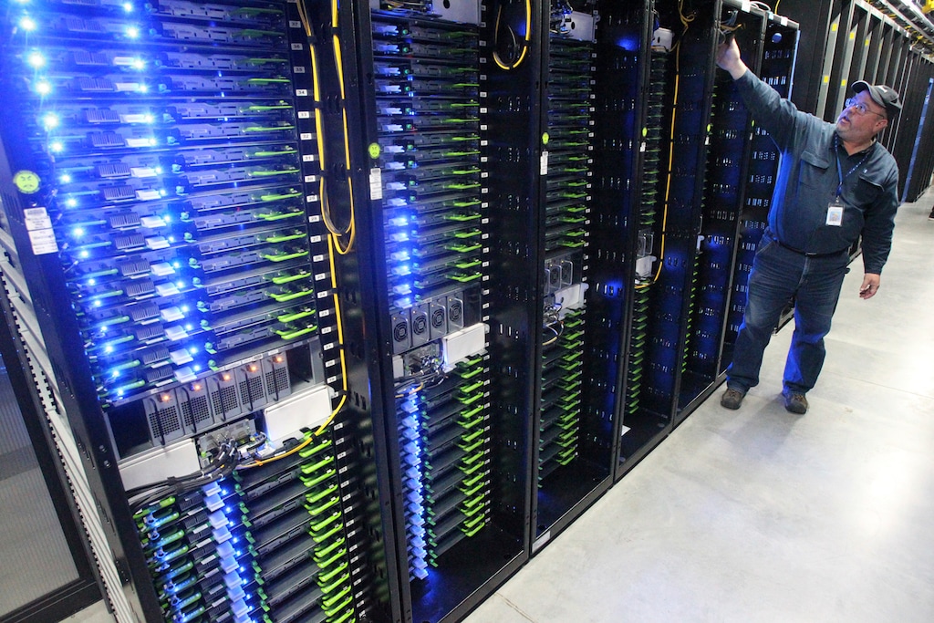 (Andy Tullis | The Bulletin file photo) In this Oct. 15, 2013, file photo, Chuck Goolsbee, site director for Facebook's Prineville data centers, shows the computer servers that store users' photos and other data, at the Facebook site in Prineville, Ore. Facebook and Apple's arrival produced a surge in electricity demand in Prineville over the past several years that has overwhelmed the Bonneville Power Administration's transmission capacity and officials are working to provide Prineville with enough electricity to ensure the central Oregon community can keep powering huge data centers operated by Facebook and Apple and make room for other companies to move in.