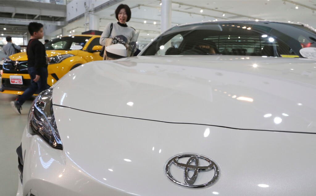 (Koji Sasahara | The Associated Press) In this Nov. 13, 2017 photo, visitors take a look at a Toyota car at its showroom in Tokyo. Toyota plans to offer more than 10 purely electric vehicle models in its lineup by the early 2020s, marking the Japanese automaker's commitment to that growing technology sector.  Toyota Motor Corp. now offers no purely electric vehicles, although it leads in hybrid models, which switch between an electric motor and a gas engine.