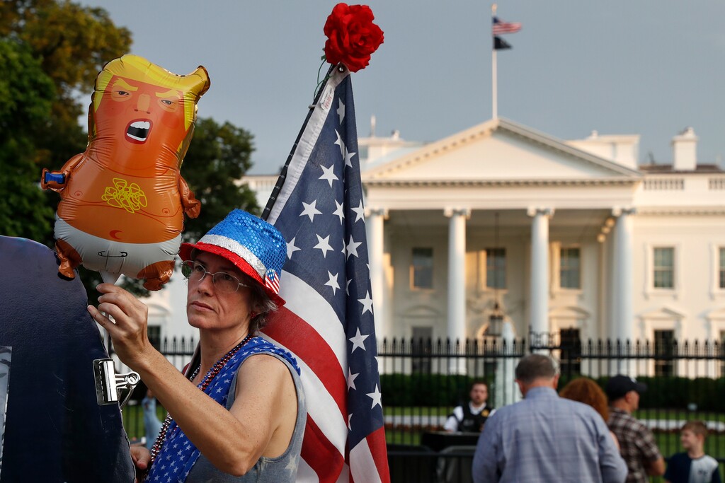 FILE - In this May 18, 2019 file photo, a woman who described herself only as "a resister" adjusts a "Trump baby" balloon at the start of a protest against President Donald Trump along Pennsylvania Ave., outside the White House in Washington. President Trump is being trolled by an angry diaper-clad caricature armed with a cell phone. It’s Baby Trump, the blimp that has become synonymous with resistance to the American president. The balloon has been cloned multiples times over and become something of a celebrity _ for at least one slice of the U.S. electorate. He’s also emerged as a rallying point for supporters of the president who see the blimp as evidence of just how over-the-top the opposition has become. (AP Photo/Jacquelyn Martin)