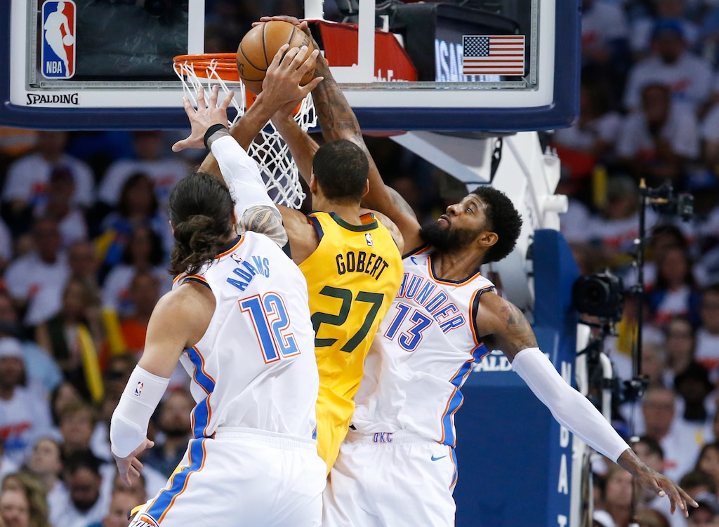 Oklahoma City Thunder forward Paul George (13) blocks a shot by Utah Jazz center Rudy Gobert (27) during the first half of Game 2 of an NBA basketball first-round playoff series in Oklahoma City, Wednesday, April 18, 2018. Thunder center Steven Adams (12) is at left. (AP Photo/Sue Ogrocki)