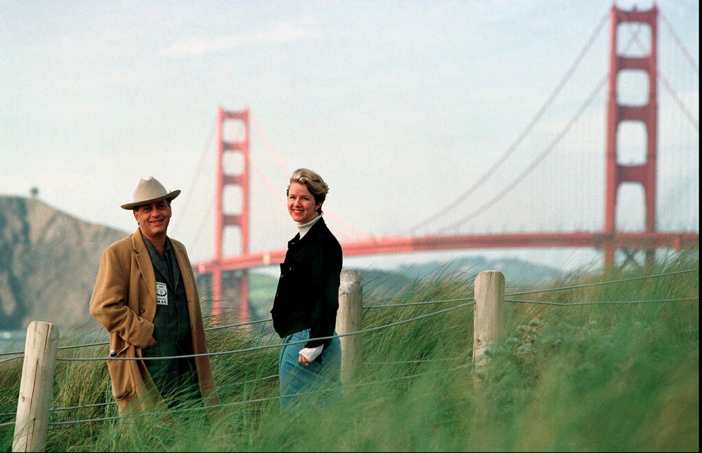 FILE - In this March 30, 1998, file photo, Larry Harvey, left, and Marian Goodell, two of the founders of the Burning Man festival walk near Baker Beach in San Francisco with the Golden Gate Bridge in the background. Harvey, the co-founder of the "Burning Man" festival has died. He was 70. Burning Man Project CEO Marian Goodell says Harvey died Saturday, April 28, 2018, morning at a hospital in San Francisco. The cause was not immediately known but he had suffered a stroke on April 4. Harvey created Burning Man on a San Francisco beach in 1986, later moving the annual event to Nevada's Black Rock Desert. (AP Photo/Eric Risberg, File)