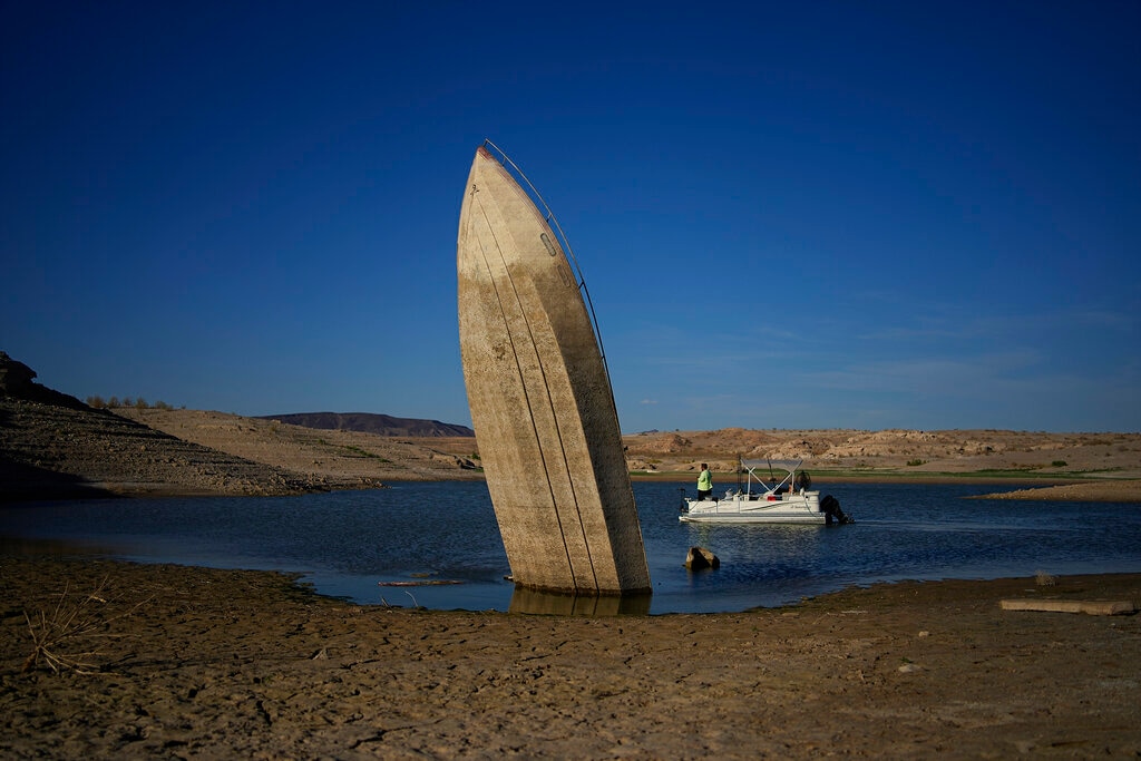 (John Locher | AP) FILE - A formerly sunken boat sits upright into the air with its stern stuck in the mud along the shoreline of Lake Mead at the Lake Mead National Recreation Area, Friday, June 10, 2022, near Boulder City, Nev. Lake Mead water has dropped to levels it hasn't been since the lake initially filled over 80 years earlier. Prolonged drought, climate change and overuse are jeopardizing the water supply that more than 40 million people rely on. States are acknowledging that painful cuts are needed, but also stubbornly clinging to the water they were allocated a century ago.
