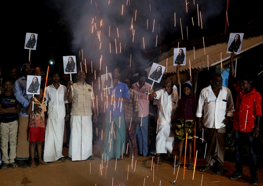 Villagers release firecrackers and hold placards featuring U.S. Vice President Kamala Harris after her inauguration, in Thulasendrapuram, the hometown of Harris' maternal grandfather, south of Chennai, Tamil Nadu state, India, Wednesday, Jan. 20, 2021. Residents of a tiny Indian village surrounded by rice paddies flocked to a Hindu temple, setting off firecrackers and praying and as they watched Kamala Harris, who has strong roots to the village, take her oath of office and become the U.S. vice president on Wednesday. (AP Photo/Aijaz Rahi)