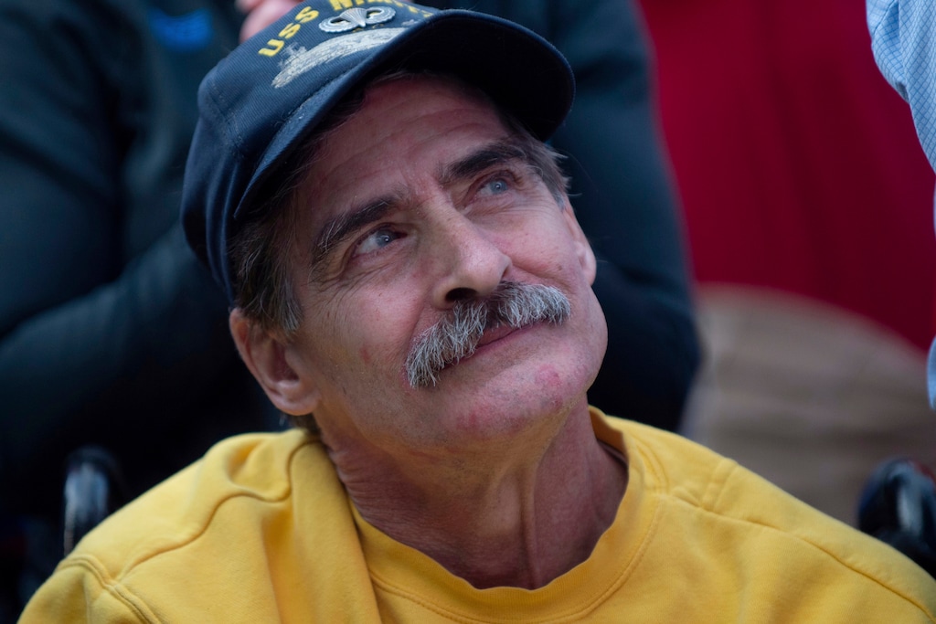 Randy Denell of Troy watches President Donald Trump during a rally on a screen outside of Van Andel Arena in Grand Rapids, Mich., on Thursday, March 28, 2019. Denell, a Trump supporter, is a U.S. veteran who served on the USS Nimitz. (Neil Blake/MLive.com/The Grand Rapids Press via AP)