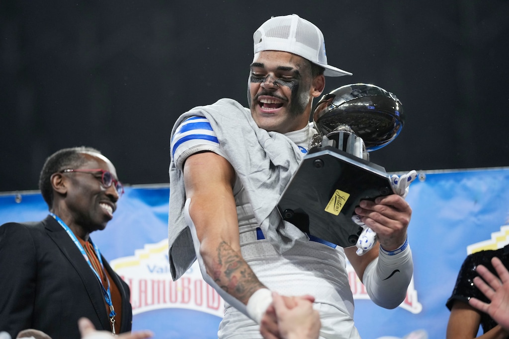 (Eric Gay | AP) BYU linebacker Isaiah Glasker (16) celebrates with his defensive play of the game trophy after the team's win over Colorado in the Alamo Bowl NCAA college football game, Saturday, Dec. 28, 2024, in San Antonio.