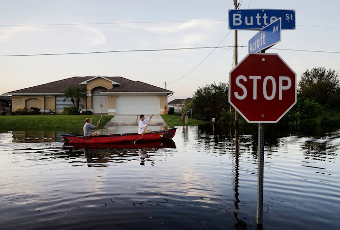 Pierre Ghantos, left, and his son Nathan paddle though their flooded neighborhood in the aftermath of Hurricane Irma in Fort Myers, Fla., Tuesday, Sept. 12, 2017. (AP Photo/David Goldman)