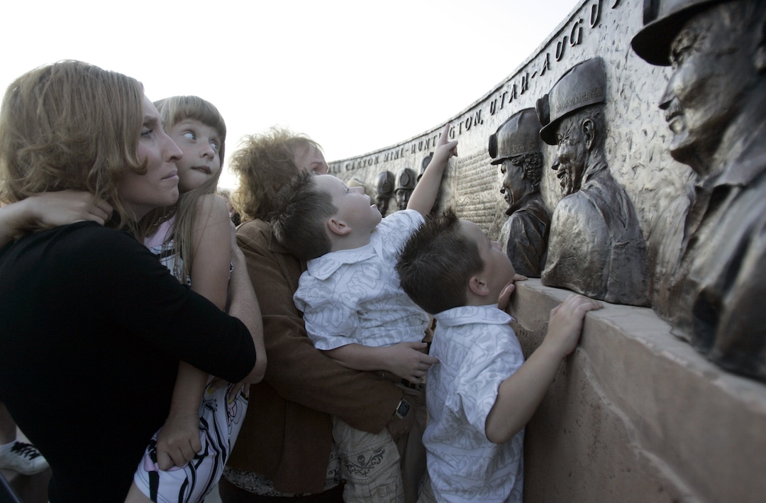 (Tribune File Photo)  Kristin Kimber, left, and her mother hold up Kristin's daughter Bryton and twin sons Peyton and Paxton to look at the image of their father, Brandon Kimber, on the Huntington memorial to the three rescuers and six miners who died in the Crandall Canyon mine disaster. The monument designed by Karen Templeton was dedicated Sept. 14, 2008.