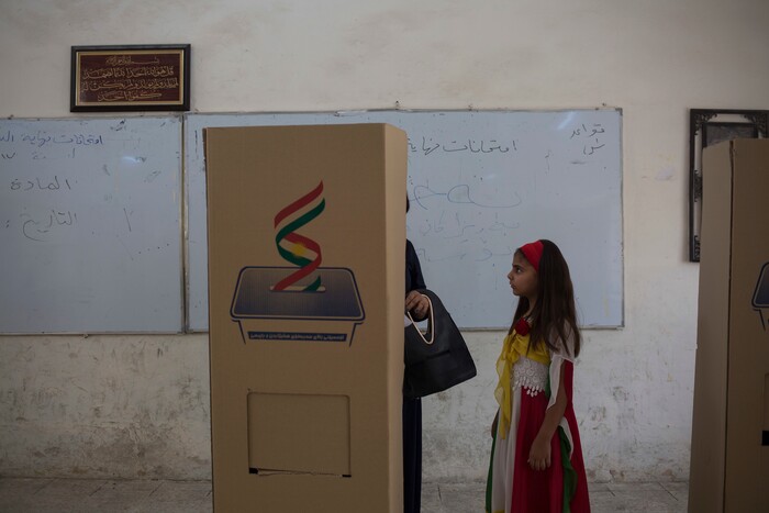 A girl dressed in the colors of the Kurdish flag looks at her mother as she votes inside the boot for Kurdish independence in the city of Kirkuk, Monday Sept. 25, 2017. Iraq's Kurdish region vote in a referendum on whether to secede from Iraq. (AP Photo/Bram Janssen)