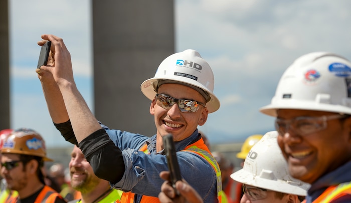 (Leah Hogsten  |  The Salt Lake Tribune) Danny Guerra and his colleagues celebrate the positioning of the last steel beam, topped with a tinsel decorated tree, during a "topping out" ceremony at the new Salt Lake City International terminal building, Wednesday, May 23, 2018. Such ceremonies can be traced to Scandinavian rites to place a tree atop a new building to appease the tree-dwelling spirits displaced during Construction.