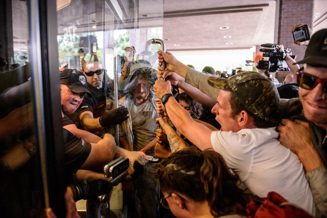 (Trent Nelson  |  The Salt Lake Tribune)  
Police struggle with Inland Port protesters for control of a door at the Chamber of Commerce Building Salt Lake City on Tuesday, July 9, 2019.