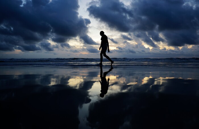(David Goldman | The Associated Press)  A man walks along the beach at sunrise ahead of Hurricane Irma in Daytona Beach, Fla., Friday, Sept. 8, 2017. Coastal residents around South Florida have been ordered to evacuate as the killer storm closes in on the peninsula for what could be a catastrophic blow this weekend.