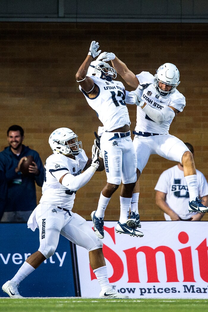 (Chris Detrick  |  The Salt Lake Tribune)  Utah State Aggies cornerback Jalen Davis (13) celebrates with Utah State Aggies safety Dallin Leavitt (2) and Utah State Aggies defensive end Adewale Adeoye (55) after scoring a touchdown off of an interception during the game at Merlin Olsen Field at Maverik Stadium Friday, September 29, 2017.