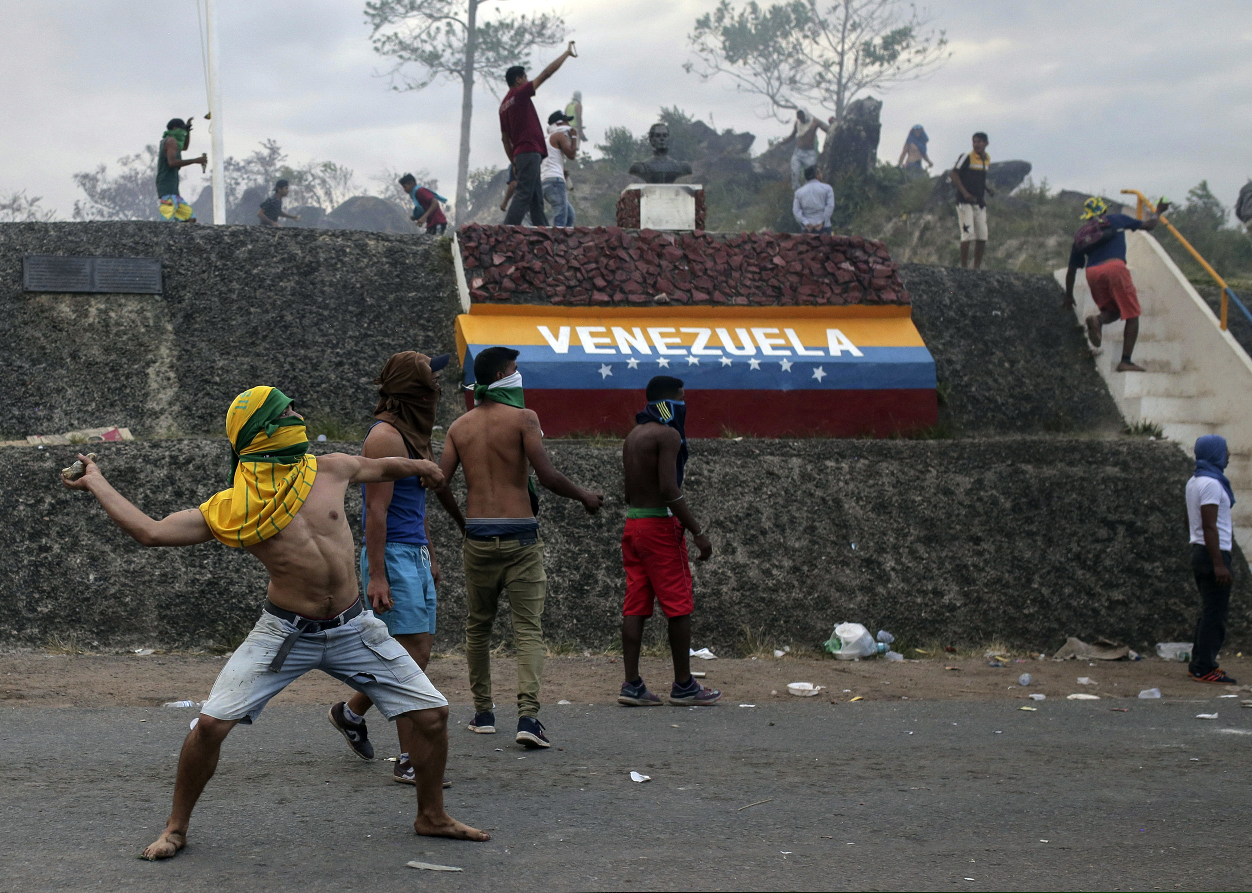 Venezuelan demonstrators throw stones during clashes with authorities, at the border between Brazil and Venezuela, Saturday, Feb.23, 2019. Tensions are running high in the Brazilian border city of Pacaraima. Thousands remained at the city's international border crossing with Venezuela to demand the entry of food and medicine.(AP Photo/Ivan Valencia)