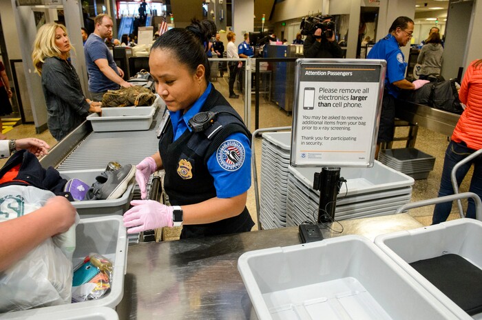 (Steve Griffin  |  The Salt Lake Tribune)  TSA agent Joyce Domingo helps airline passengers as they go through security at Salt Lake International Airport Thursday October 5, 2017. TSA has implemented stronger carry-on baggage screening for electronic devices where any electronic device larger than a cell phone needs to be in bins for X-ray.