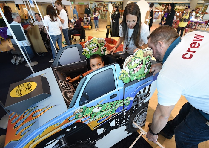 (Francisco Kjolseth  |  The Salt Lake Tribune)  Jonathan Clark, 6, sits inside his new monster truck as Claire Behnke and Mitch Peace modify a wheelchair costume kit along with other volunteers and staff at Shriners Hospital for Children in Salt Lake on Wednesday, Oct. 17, 2018.