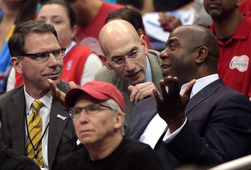 FILE - In this May 11, 2014, file photo, NBA Commissioner Adam Silver, center, talks with Magic Johnson, right, as Kiki Vandeweghe looks on as they watch the Los Angeles Clippers play the Oklahoma City Thunder in the first half of Game 4 of the Western Conference semifinal NBA basketball playoff series, in Los Angeles. The NBA will experiment with a coaches' challenge for summer league games, one where teams will have the ability to seek a review of certain calls in the final 2 minutes of regulation and overtime. Coaches will have to call a time-out before live play resumes, and then trigger a blinking light on the scorer's table to initiate the challenge. "We're going to try it in limited form," NBA executive vice president for basketball operations Kiki Vandeweghe said.(AP Photo/Mark J. Terrill, FIle)