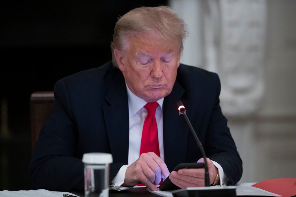 President Donald Trump looks at his phone during a roundtable with governors on the reopening of America's small businesses, in the State Dining Room of the White House, Thursday, June 18, 2020, in Washington. (AP Photo/Alex Brandon)
