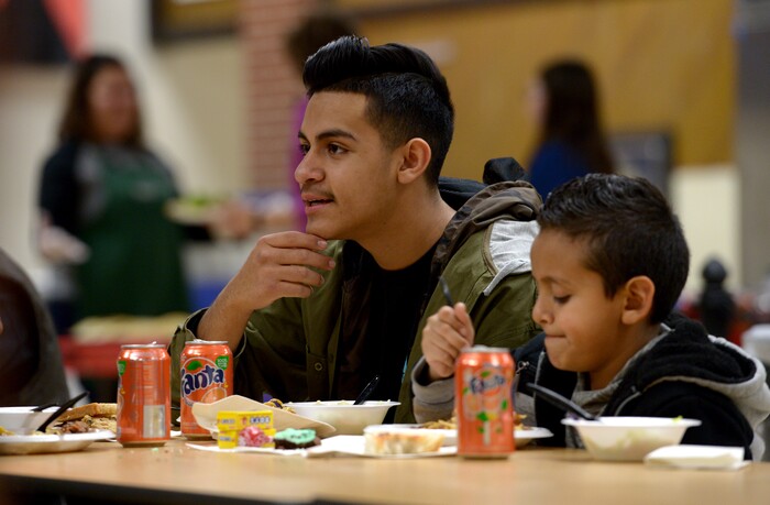 (Leah Hogsten  |  The Salt Lake Tribune) l-r Oscar Seranno, 13, and his brother Joel eat dinner with their father. Oscar attends seventh grade at Granite Park Junior High. Sixteen members of Granite Park Junior High SchoolÕs faculty prepared and served a hot spaghetti meal to students and their families, Friday, December 22, 2017 at the school for the inaugural ÔDinner at the Park.' Roughly 90 percent of students who attend Granite Park Junior High in South Salt Lake qualify for free or reduced lunch through the federal school lunch program. Knowing the challenges faced by their students, staff members at Granite Park came up with an idea to help families through the holidays.