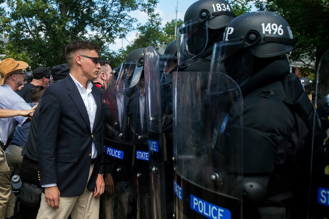A protester stands in front of  state troopers during a white nationalist rally on Saturday Aug. 12, 2017, in Charlottesville, Va. The group had gathered to protest plans by the city of Charlottesville to remove a statue of Confederate Gen. Robert E. Lee. (Shaban Athuman /Richmond Times-Dispatch via AP)