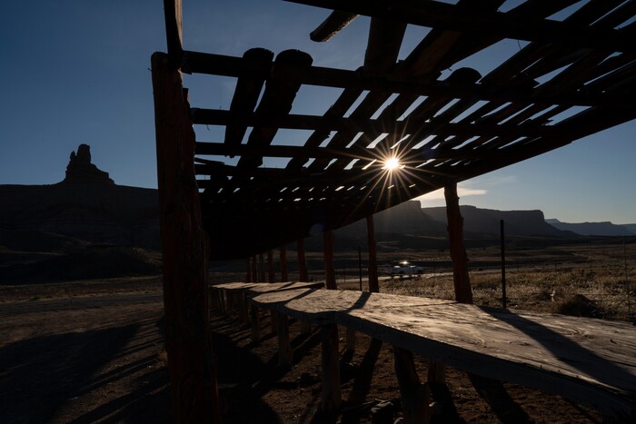A Navajo market table stands unused as Doggy Rock is seen across Interstate 163 in Monument Valley north of Kayenta, Ariz., on the Navajo reservation on April 28, 2020. Navajo Monument Vally Tribal Park is closed in an effort to prevent the spread of COVID-19 on the Navajo reservation. (AP Photo/Carolyn Kaster)