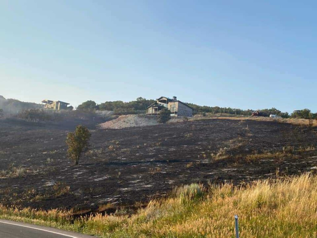 (Weber Fire District) Grass is blackened close to homes after gunfire sparked a blaze near Snowbasin Resort in Weber County.
