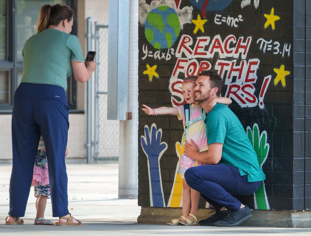 (Leah Hogsten | The Salt Lake Tribune) Kindergartener Elise Huntington, 5, reaches out to her sister Vivian 2, to join her and her father Matt as her mother Kaitlin takes photos on the first day of school at Mary W. Jackson Elementary, August 22, 2023.