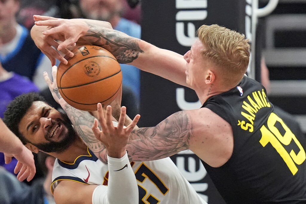 Denver Nuggets guard Jamal Murray, left, and Utah Jazz forward Luka Samanic (19) battle for the ball during the first half of an NBA basketball game Tuesday, April 9, 2024, in Salt Lake City. (AP Photo/Rick Bowmer)