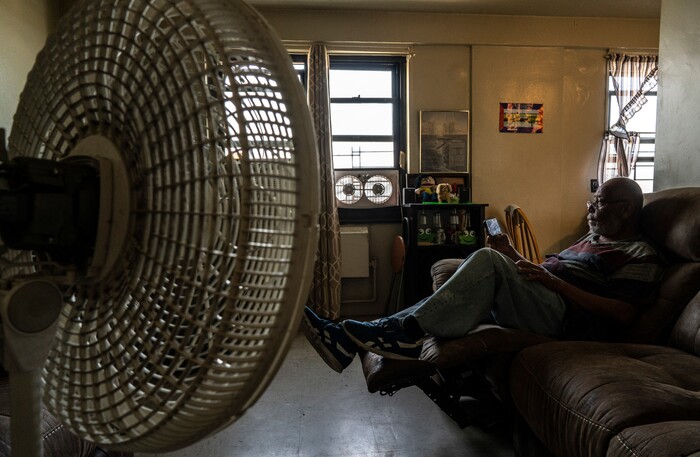 (Juan Arredondo | The New York Times) Rafael Velasquez, a retired cook who lives alone since his wife passed, keeps cool with fans at the Carter G. Woodson Senior house in Brooklyn, July 23, 2020. Around the world, the poor and marginalized are much more likely to be vulnerable to extreme heat; Black people and Latinos like Velasquez are far more likely to live in the hottest parts of American cities.