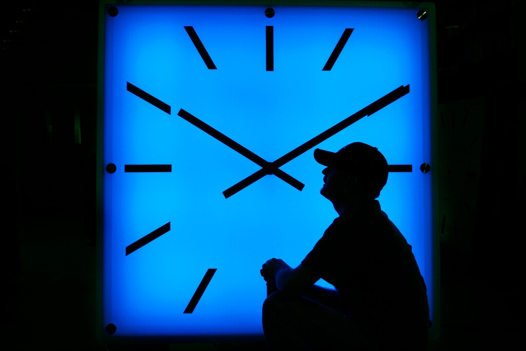 (Elise Amendola | The Associated Press) In this Oct. 30, 2008, file photo, Electric Time Company employee Dan Lamoore adjusts the color on a 67-inch square LED color-changing clock at the plant in Medfield, Mass. 
