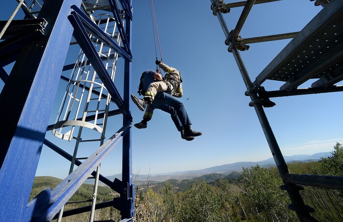 (Scott Sommerdorf | The Salt Lake Tribune) Firefighter Rob Takeno, top, of the Park City Fire District special operations team practices a tower crane operator rescue with firefighter Steve Jensen, left, acting as the victim, as they are slowly lowered to the ground. The high mountain rescue training exercise utilized a Jacobsen tower crane and operator at the construction site of the One Empire Pass development at Deer Valley, Sunday, Aug. 20, 2017.