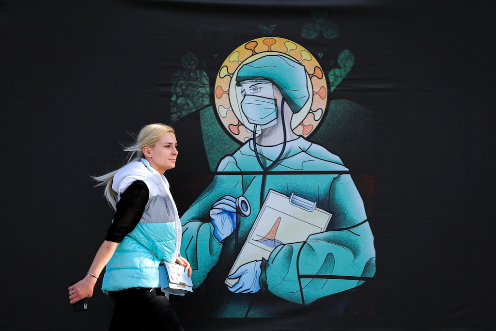 (Vadim Ghirda | AP) A woman walks by a depiction of a medical staff wearing protective equipment, executed in the style of orthodox icons, in Bucharest, Romania, Wednesday, April 29, 2020. The artwork, among others depicting medical staff in the manner of religious icons, created by designer Wanda Hutira, is part of a campaign called Thank You Doctors, meant to raise awareness to the work of medical staff fighting the COVID-19 pandemic. Following public pressure by Romania's influential Orthodox church the artworks, described as "blasphemous" will be removed from all locations in the Romanian capital, according to the agency behind the project.