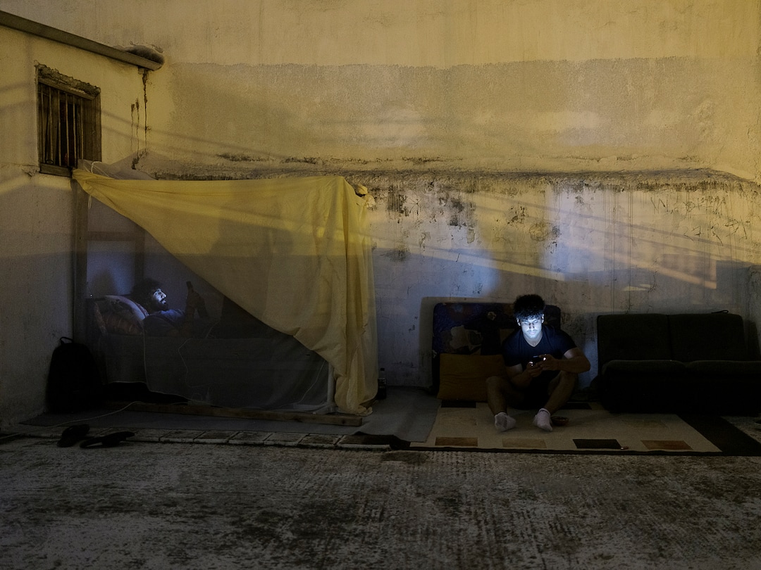 (Myrto Papadopoulos | The New York Times) Hasib Hotak, right, a homeless refugee from Afghanistan, and a friend on the rooftop where they sleep at night in Athens, Greece, July 22, 2020. Around the world, the poor and marginalized are much more likely to be vulnerable to extreme heat; Hasib's rooftop refuge turns blazing hot by midday.
