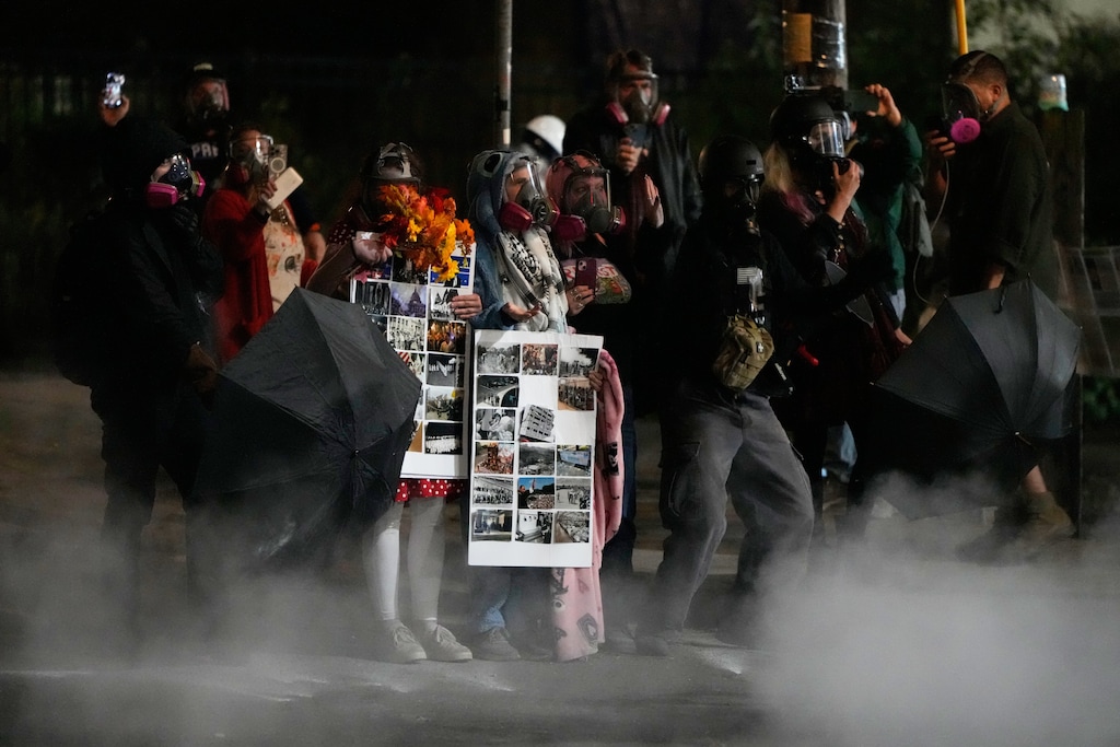 Tear gas drifts by demonstrators outside a U.S. Immigration and Customs Enforcement facility during a protest on Saturday, Oct. 4, 2025, in Portland, Ore. (AP Photo/Jenny Kane)