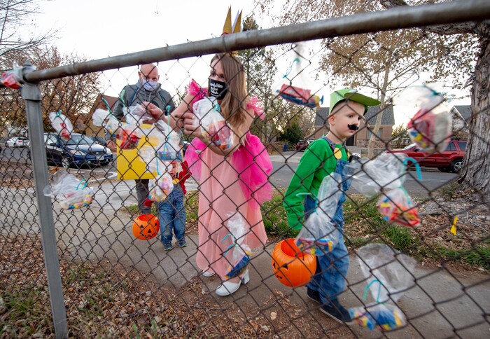 (Francisco Kjolseth  |  The Salt Lake Tribune) Andrea and Rob Byron trick or treat with their kids Harvey, 1, and Leo, 5, as they pull treat bags off a fence from a household agreeing to abide by CDC Covid safety standards on Saturday, Oct. 31, 2020 in Sugar House.