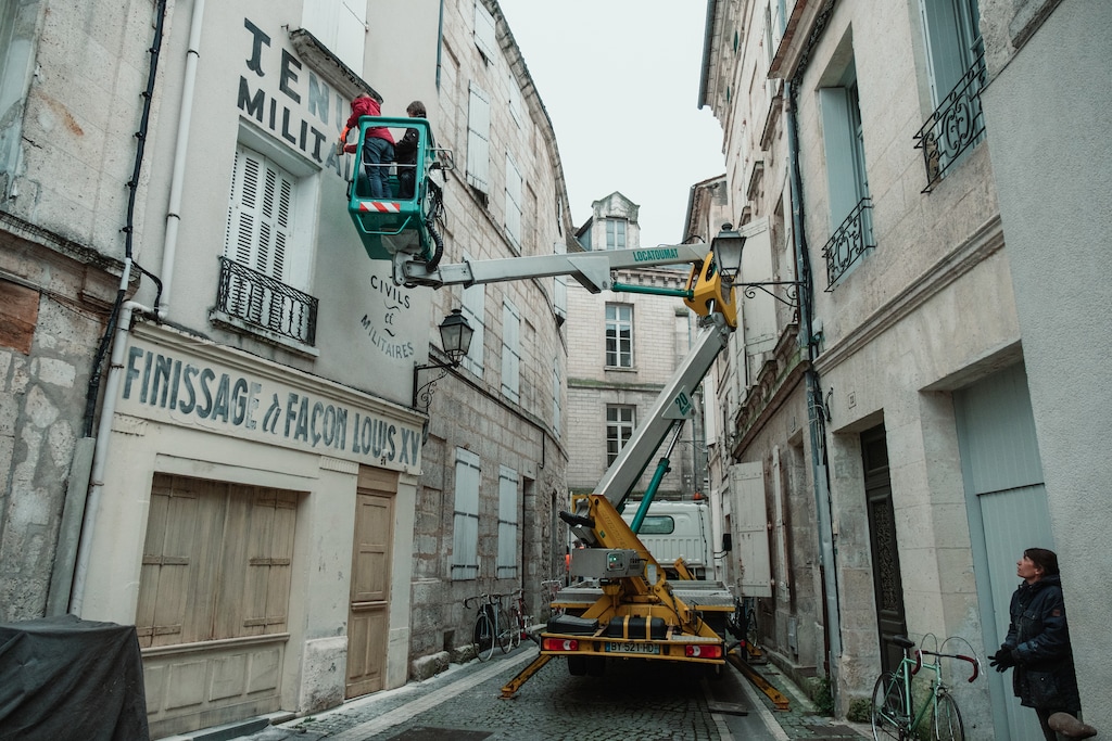 In a photo provided by Roger Do Minh, The crew paints signs on building walls for shots in the Wes Anderson film. For “The French Dispatch,” the filmmakers set up shop in a real French city to create the setting for the movie’s fictional one. (Roger Do Minh via The New York Times)