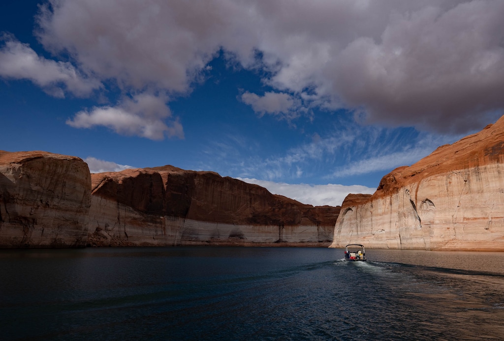 (Francisco Kjolseth | The Salt Lake Tribune) A Lake Powell rental pontoon boat motors down the main channel of the reservoir on Saturday, April 25, 2026, as bathtub rings are indicative of how far the waters levels have fallen since being at full capacity in the early 1980s. 