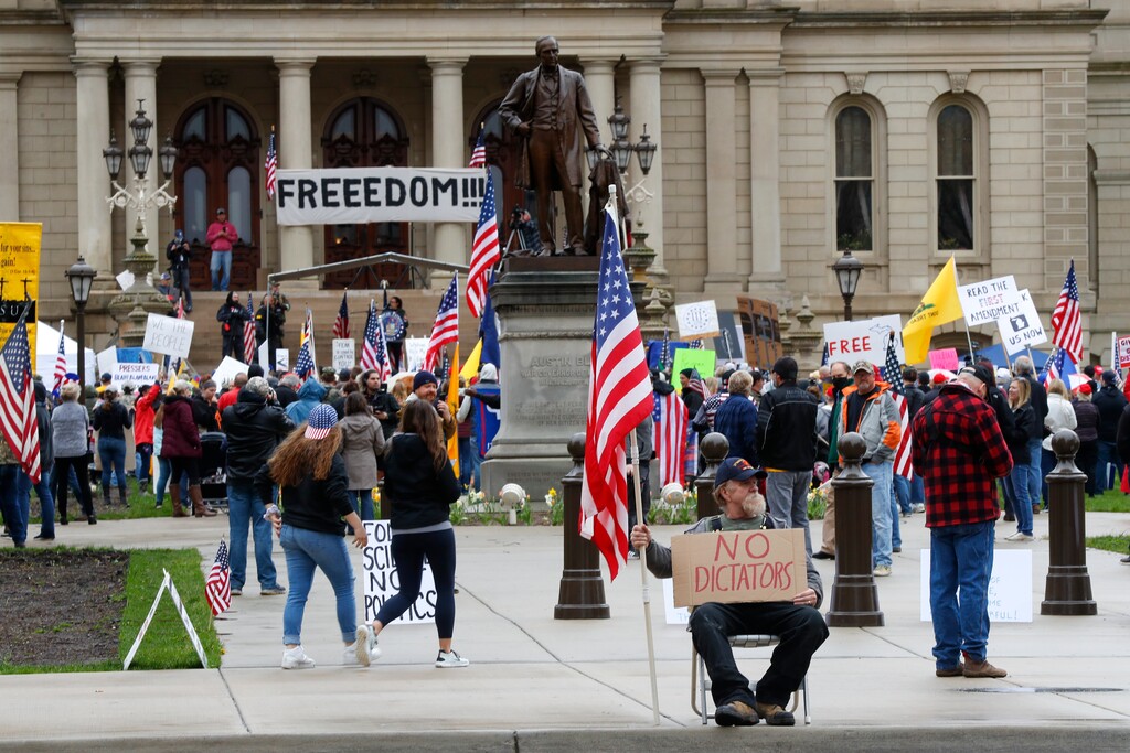 (Paul Sancya | AP) In this April 30, 2020, photo, protesters rally at the State Capitol in Lansing, Mich. Gun-carrying protesters have been a common sight at some demonstrations calling for coronavirus-related restrictions to be lifted. But an armed militia’s involvement in an angry protest in the Michigan statehouse Thursday marked an escalation that drew condemnation and shone a spotlight on the practice of bringing weapons to protest.