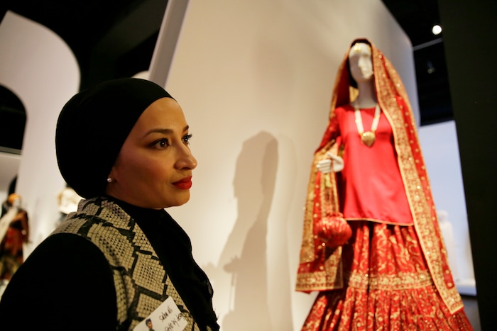 (Eric Risberg  |  AP Photo)  In this photo taken Thursday, Sept. 20, 2018, stylist Saba Ali talks about her Pakistani wedding ensemble of red silk and chiffon in the exhibit Contemporary Muslim Fashions at the M. H. de Young Memorial Museum in San Francisco. The first major museum exhibition of contemporary Muslim women's fashion reflects designs from around the world that are vibrant and elegant, playful and diverse. The show's creators hope the exhibit will show Muslim women as real people who can choose what they wear rather than as subjects ordered to cover their entire bodies or restricted in what they can wear. The exhibit opens on Saturday.