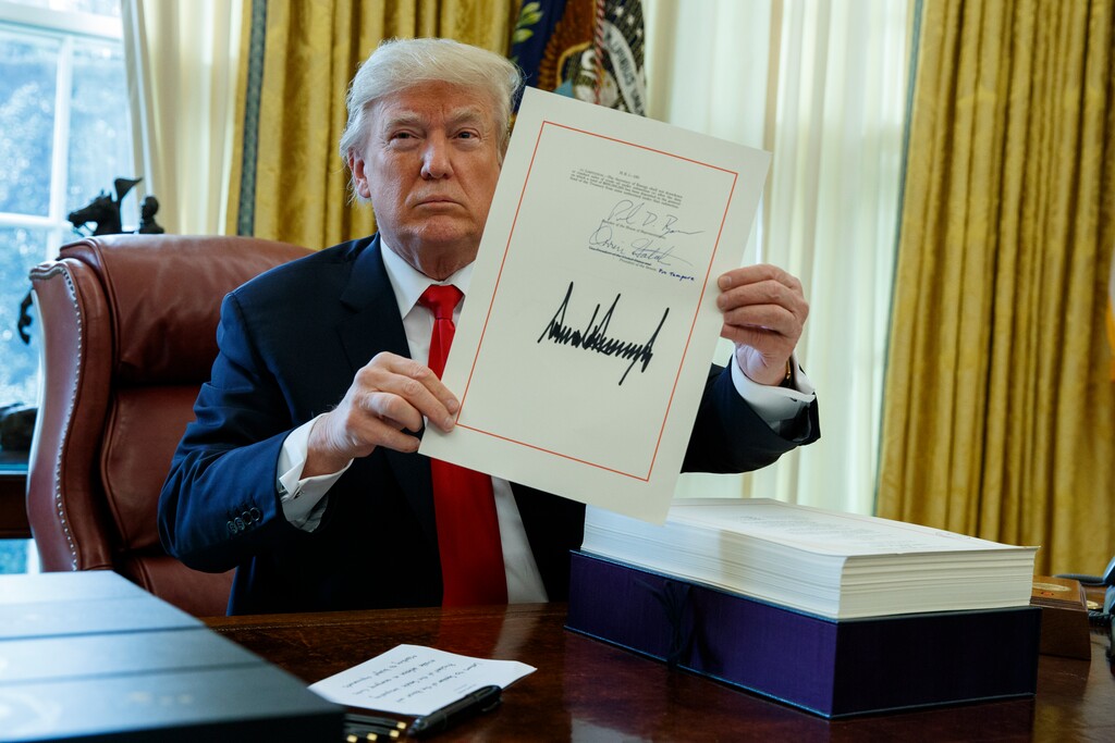 President Donald Trump shows off the tax bill after signing it in the Oval Office of the White House, Friday, Dec. 22, 2017, in Washington. (AP Photo/Evan Vucci)